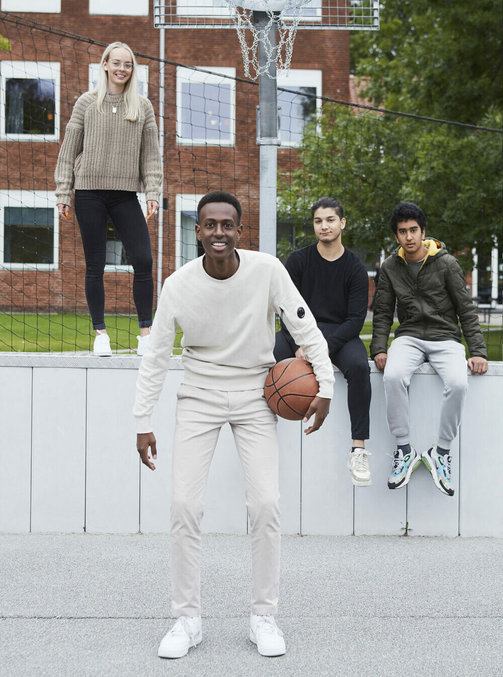4 unge på en basketballbane. En ung mand er i front med en basketball.